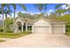 Tan three-car garage stucco home with palm trees and landscaped yard at 10106 Radcliffe Dr, Tampa, FL 33626