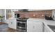 Kitchen featuring stainless steel appliances, white cabinets, and tile backsplash at 5524 Kentucky Ave, New Port Richey, FL 34652