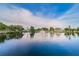 Scenic pond view featuring a fountain, mature trees, palm trees, and waterfront homes at 5524 Kentucky Ave, New Port Richey, FL 34652