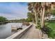 Waterfront walkway with a concrete wall, benches, grassy areas, palm trees, and docks for boats and kayaks at 5524 Kentucky Ave, New Port Richey, FL 34652