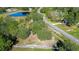 Aerial view of vacant lot with white fence, pond, and trees at 8345 Shenandoah Run, Wesley Chapel, FL 33544