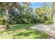 Green grassy backyard with a brick patio and tropical plants at 2122 Oak Forest Ln, Palm Harbor, FL 34683