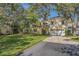 Two-story house with a large yard, driveway and mature trees at 2122 Oak Forest Ln, Palm Harbor, FL 34683