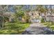 Two-story house with a large yard, driveway and mature trees at 2122 Oak Forest Ln, Palm Harbor, FL 34683