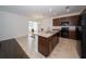 Modern kitchen with dark brown cabinets, an island, and a glass-top dining table at 2941 Adams Cross Dr, Zephyrhills, FL 33540