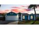 House exterior at dusk; teal with white garage door at 8436 Red Roe Dr, New Port Richey, FL 34653
