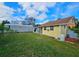 Landscaped backyard with a yellow house, detached garage, and storage building at 7211 Waycross Ave, Tampa, FL 33619