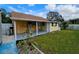 Backyard view showcasing a yellow house, covered patio, and grassy lawn at 7211 Waycross Ave, Tampa, FL 33619