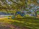 playground with slides and play structures under shady trees at 1611 Brook Dr, Dunedin, FL 34698