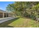 Inviting outdoor space with a screened-in porch, grassy yard, and bordering trees for added privacy at 3203 Audubon Ct, Tarpon Springs, FL 34688