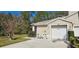 Home's exterior showcasing the garage, driveway, and well-kept front yard with mature plants at 3203 Audubon Ct, Tarpon Springs, FL 34688
