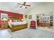 Large main bedroom with wood furniture, ensuite office, and red accent wall at 8037 Shaddock Pl, Land O Lakes, FL 34637