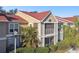 Tan condo building with red tile roof, screened balcony, and palm trees at 9481 Highland Oak Dr # 807, Tampa, FL 33647