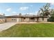 Rear view of tan house with solar panels, stone patio, and grassy yard at 2609 65Th E St, Bradenton, FL 34208