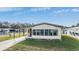 Tan mobile home with carport and landscaped lawn at 35934 Verano Ln, Zephyrhills, FL 33541