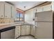 L-shaped kitchen with white cabinets, stainless steel dishwasher, and a refrigerator at 35934 Verano Ln, Zephyrhills, FL 33541
