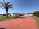 Ranch-style home with a red driveway and palm tree at 10 Golfview S Rd, Rotonda West, FL 33947