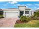 Well-kept single-story home with a two-car garage, brick driveway, green lawn, and tropical landscaping at 11312 Gallatin Trl, Parrish, FL 34219