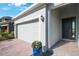 Close up of a well-maintained exterior featuring a bright white garage door, brick driveway, and a contemporary styled front door at 11312 Gallatin Trl, Parrish, FL 34219