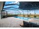 A screened-in pool area with a luxurious patio, umbrella, and comfortable seating under a clear blue sky at 11312 Gallatin Trl, Parrish, FL 34219