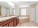 Bathroom with double vanity, soaking tub and tile floor at 13419 Lake Monroe Pl, Riverview, FL 33579