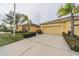Two-car garage with driveway, landscaping, and a yellow exterior at 2311 Nottingham Greens Dr # 2311, Sun City Center, FL 33573