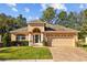 Tan one-story house with a two-car garage, landscaped lawn, and a stone driveway at 4275 Caskie Pl, Brooksville, FL 34604