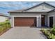 Home's exterior showcases a brown garage door and a brick paved driveway at 12626 Tahitian Pearl Cir, Parrish, FL 34219
