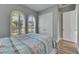 Bedroom with wood-look floors, white bed, and arched windows with shutters at 13307 Fawn Lily Dr, Riverview, FL 33579