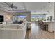 Open living room with large sectional sofa, wood-look tile floors, and view of the backyard and pool at 13307 Fawn Lily Dr, Riverview, FL 33579