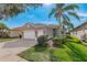 Single-story home with a two-car garage, landscaping, and a paved driveway at 16121 Coquina Bay Ln, Wimauma, FL 33598