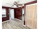 Bedroom with maroon walls, wood-look floors, and ceiling fan at 3148 Harvardston Loop, Holiday, FL 34691