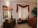 Bedroom with a dresser, mirror, and window with red curtains at 7108 Saint Andrews Ln, Sarasota, FL 34243