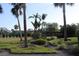 Landscaped lawn with tropical plants and palm trees near tennis courts at 7108 Saint Andrews Ln, Sarasota, FL 34243