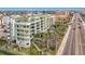 Aerial view of a building near a busy road with palm trees and a pool at 11605 Gulf Blvd # 505, Treasure Island, FL 33706