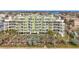 Aerial view of a light-green building, pool, and lush landscaping at 11605 Gulf Blvd # 505, Treasure Island, FL 33706