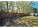 Landscaped backyard with a wooden fence, grass, and mature trees at 1597 Franklin Way, Dunedin, FL 34698