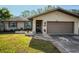 Tan house exterior with brown garage door and walkway at 1597 Franklin Way, Dunedin, FL 34698