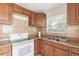 Kitchen with wooden cabinets, white appliances, and granite countertops at 1310 Preston S St, St Petersburg, FL 33712