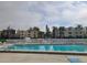 Community pool with surrounding lounge chairs and building view at 14130 Rosemary Ln # 6214, Largo, FL 33774