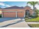 Two-story house with orange walls, two-car garage, and lush green landscaping at 613 Tanana Fall Dr, Ruskin, FL 33570