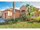 Front view of two-story house with orange exterior, palm trees, and well-manicured lawn at 613 Tanana Fall Dr, Ruskin, FL 33570