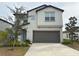 Two-story house with gray siding, brown garage door, and landscaping at 6300 Beverly Hills Dr, Zephyrhills, FL 33541