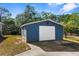 Detached gray garage with a white roll-up door at 25888 Whipperwill St, Brooksville, FL 34601