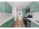 Modern kitchen with white countertops, stainless steel appliances, and teal cabinets at 25888 Whipperwill St, Brooksville, FL 34601