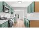 Modern kitchen with white countertops, stainless steel appliances, and teal cabinets at 25888 Whipperwill St, Brooksville, FL 34601