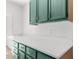 White countertops and teal cabinets offer ample storage in this kitchen at 25888 Whipperwill St, Brooksville, FL 34601