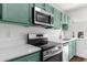 Stainless steel appliances and teal cabinets in this updated kitchen at 25888 Whipperwill St, Brooksville, FL 34601