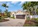 House exterior showcasing a two-car garage and lush landscaping at 1879 Nuthatch Way, Palm Harbor, FL 34683