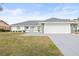 White single-story house with gray roof, two-car garage, and landscaped front yard at 2024 N Pebble Beach Blvd, Sun City Center, FL 33573